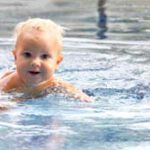 Cute baby swims in a swimming pool in summer