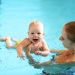 healthy family mother teaching baby swimming pool